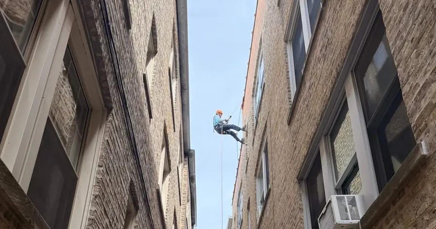 No Room for a Ladder: Cleaning a 4th-Floor Dryer Vent in a Chicago Gangway Rope access technician suspended between two Chicago brick buildings in a narrow gangway to reach a fourth-floor dryer vent
