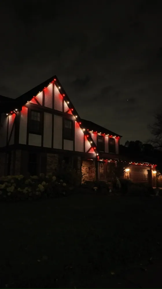 The same Tudor home with its permanent roofline lighting set to red and white for Valentine's Day
