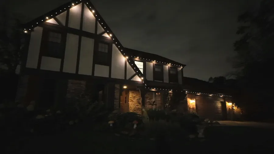 Tudor style home with permanent roofline lighting running warm white along every gable and eave on an ordinary evening