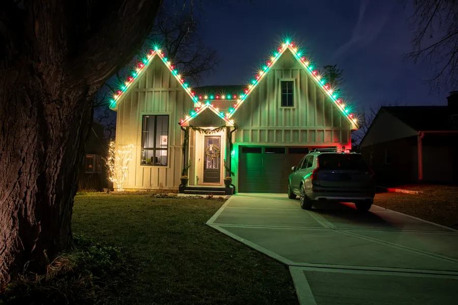 Suburban home outlined in red and green C9 bulbs along every roofline peak and the garage, photographed at dusk