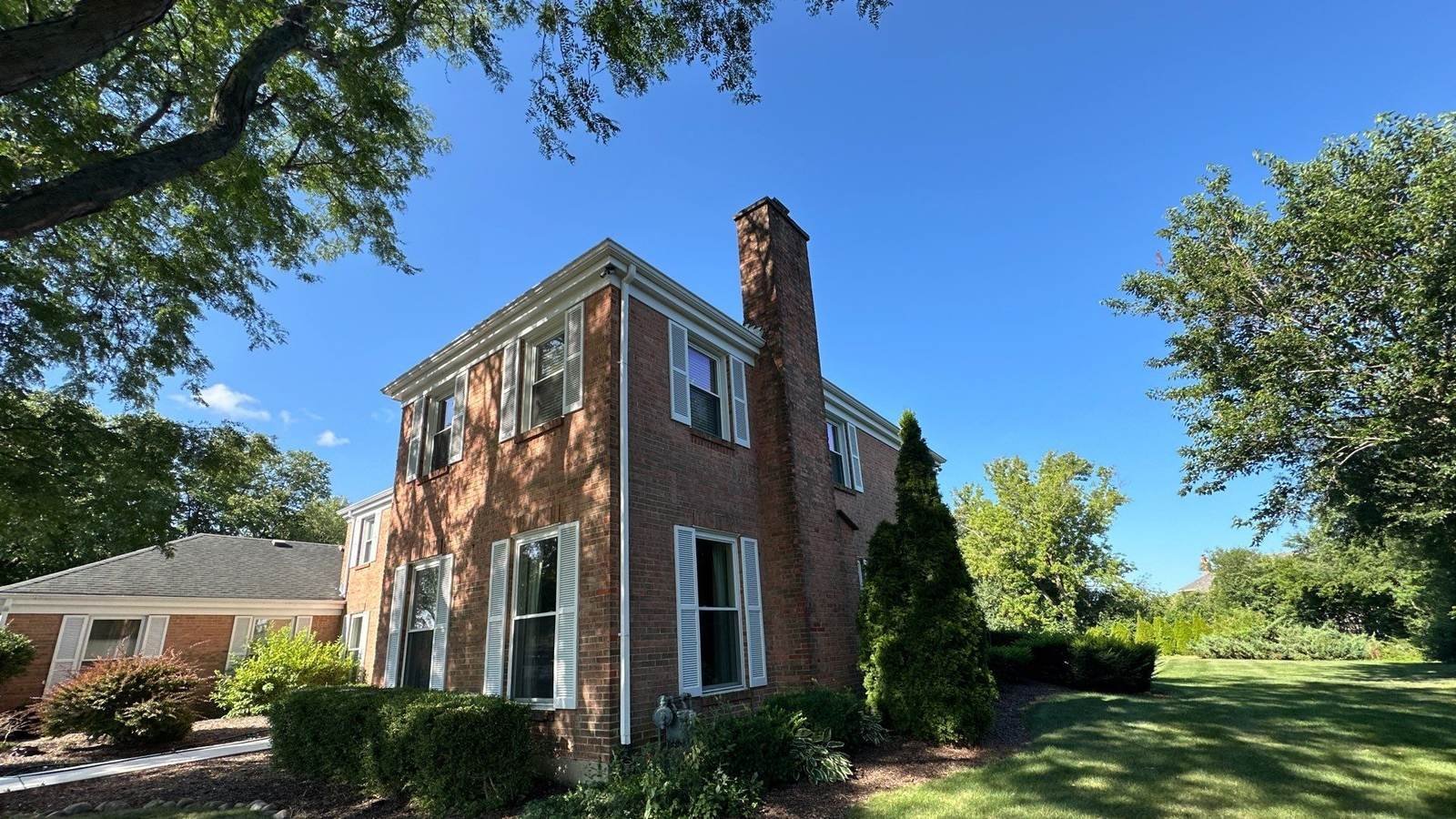 Brick colonial home under a mature oak canopy cleaned by Pane Pal