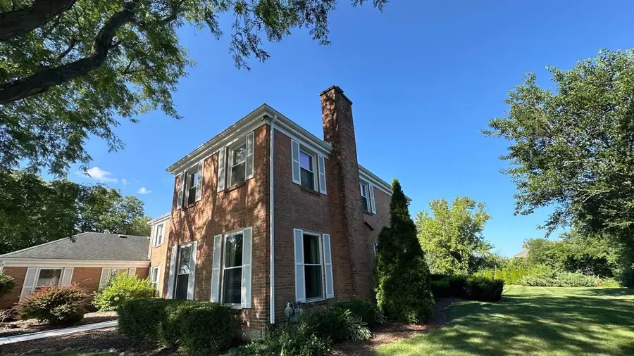 Brick colonial home under a mature oak canopy cleaned by Pane Pal