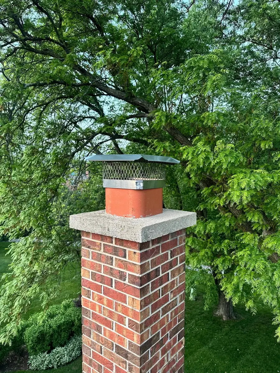 Brick chimney with installed rain cap preventing water and animal entry